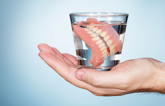 Full set of dentures in a glass of water