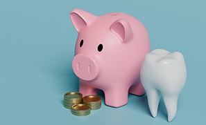 A piggy bank and model tooth next to some coins