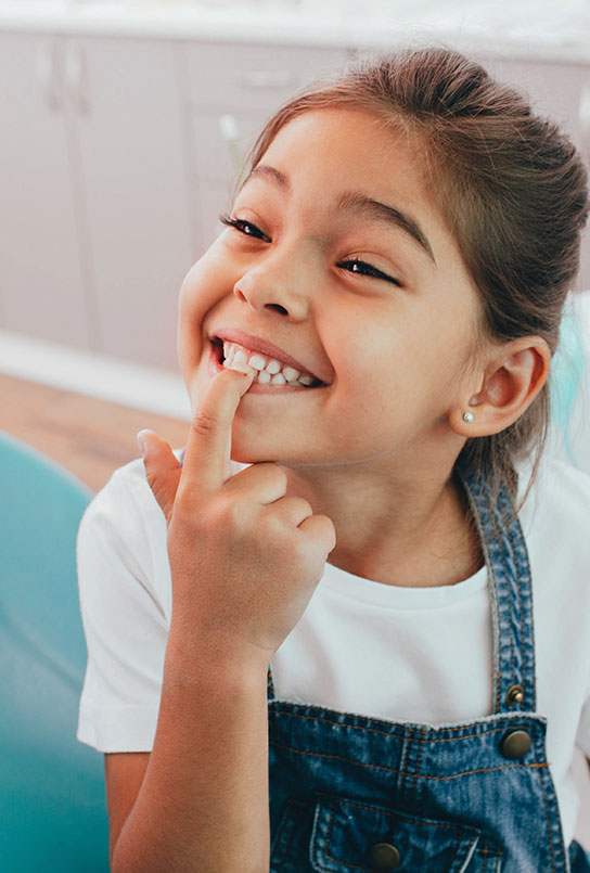 Child pointing to smile after children's dentistry visit