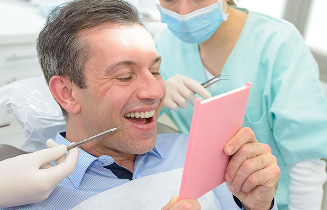 Man looking at smile after dental crown restoration