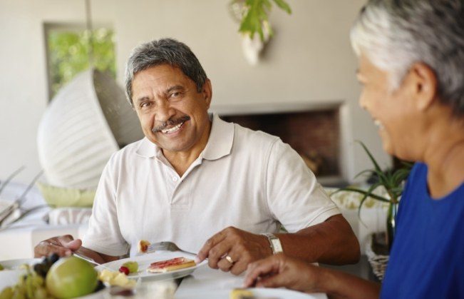 Man smiling and enjoying a meal with a friend