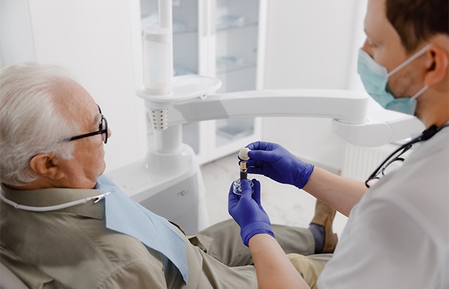 Dentist explaining concept of dental implants to senior patient