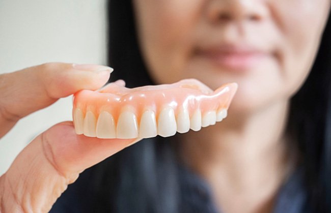 Woman holding dentures