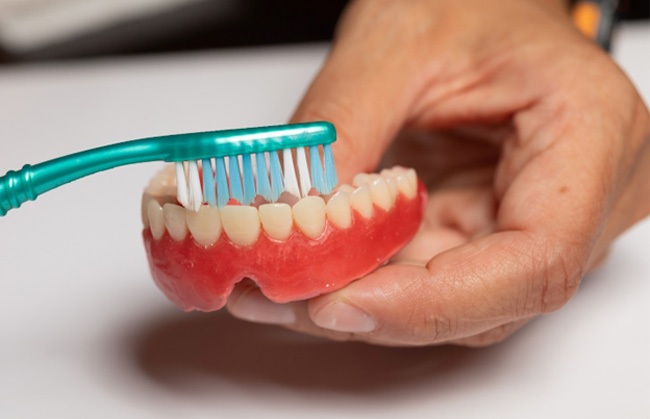 Man brushing his dentures