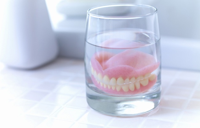 Dentures soaking in a glass of water