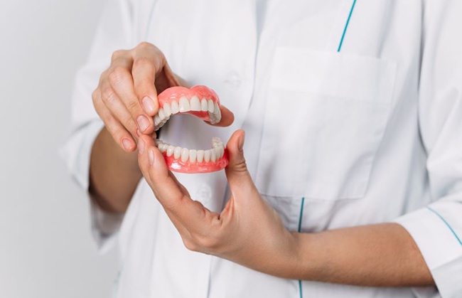 Dental professional holding upper and lower dentures