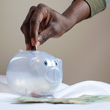 Hand putting coin in piggy bank