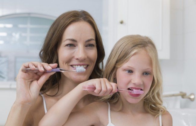 Mother and daughter brushing teeth together