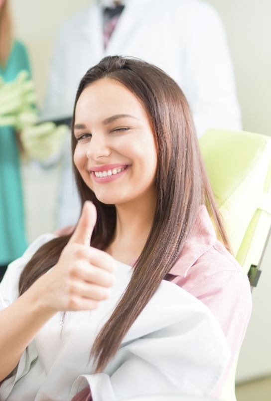 Smiling woman giving thumbs up after wisdom tooth extractions
