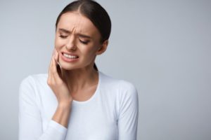 woman holding her jaw in pain