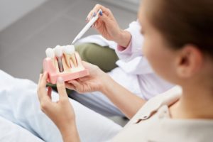 woman holding dental implant model during consultation 