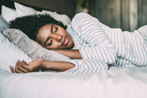 Young woman in striped shirt sleeping in bed