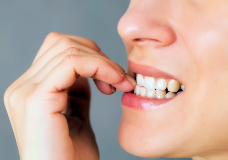 A closeup of a woman biting her nails