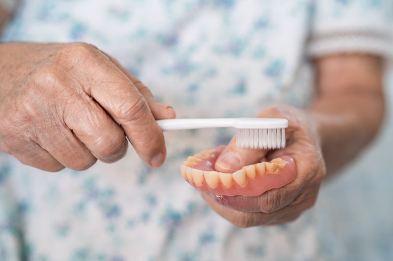 a person brushing their dentures