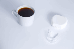 a cup of coffee next to an Invisalign tray